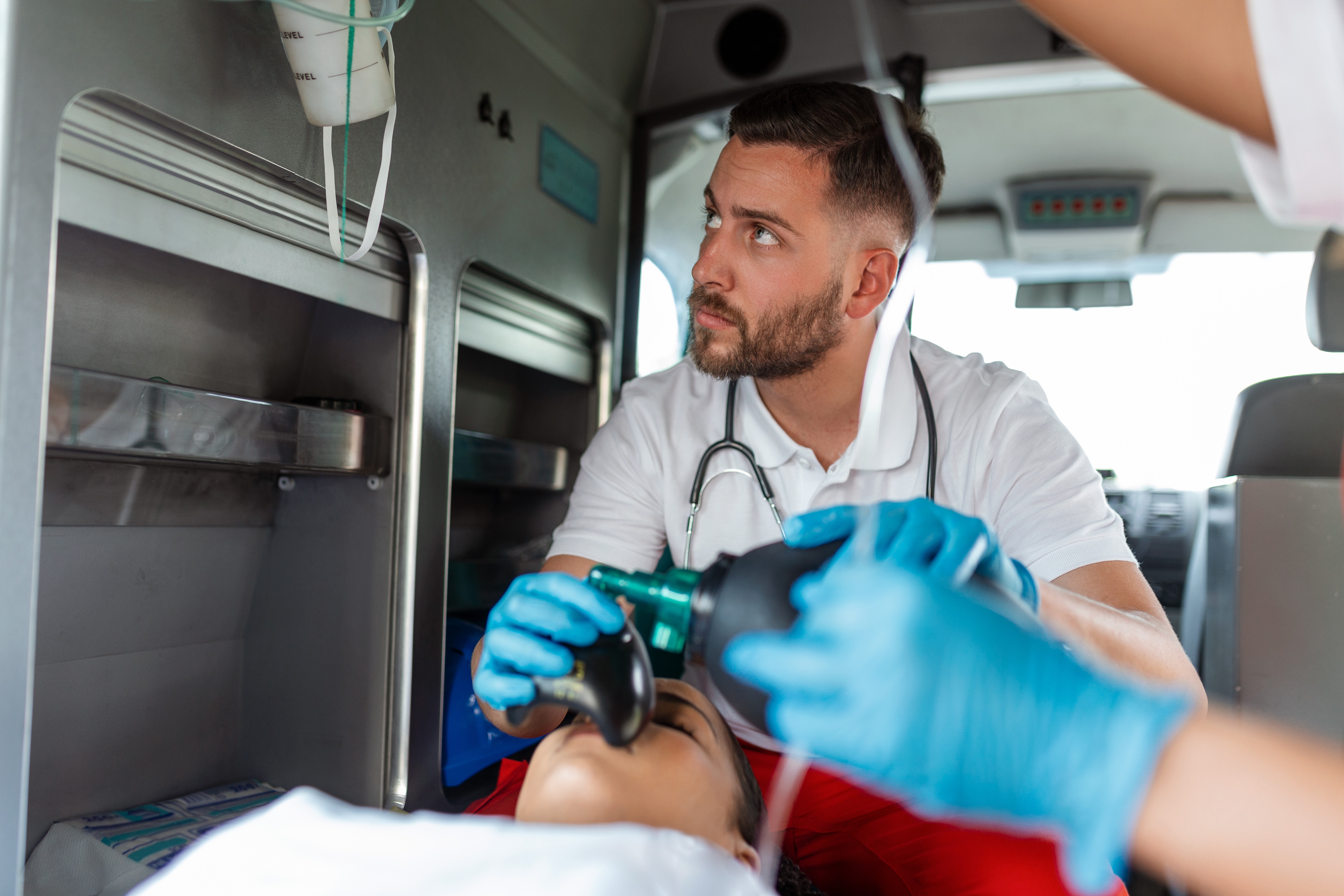 EMS Paramedics Team Provide Medical Help to Injured Patient on the Way to Healthcare Hospital. Emergency Care Assistant Using a Non-Invasive Ventilation Mask in an Ambulance. Close-up Shot.